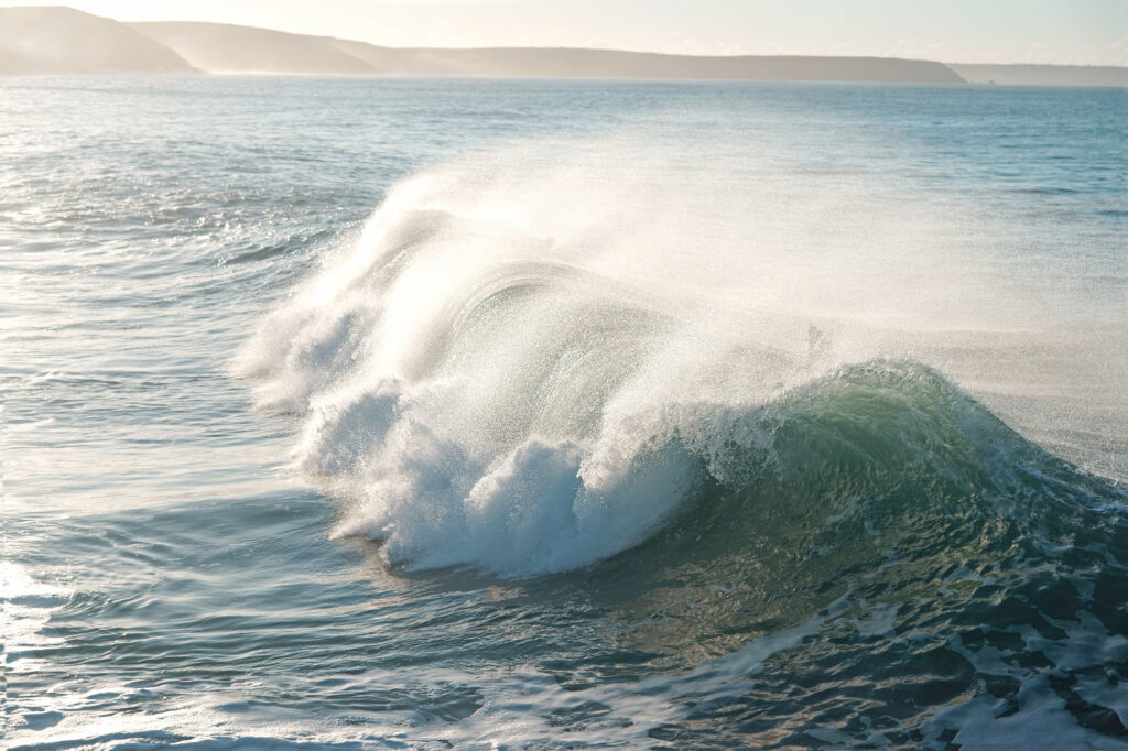 surf camps Bude. Waves breaking with spray off the back.