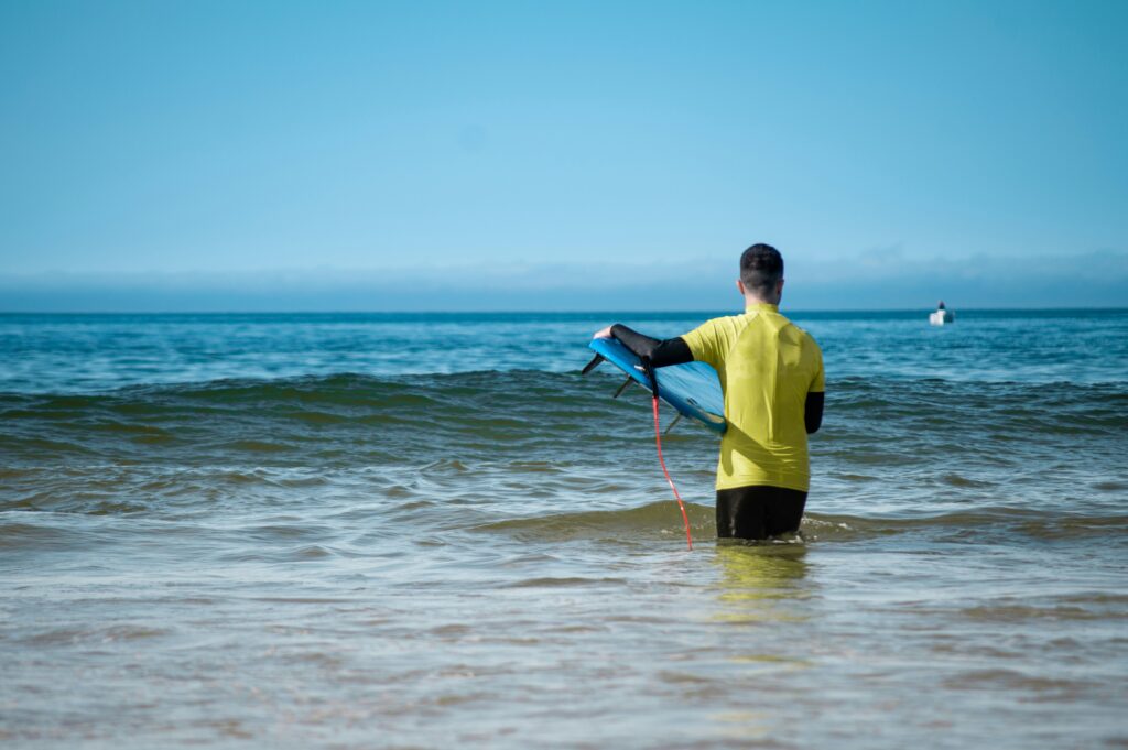 surf lessons near me. learning surfer carrying his board through the waves