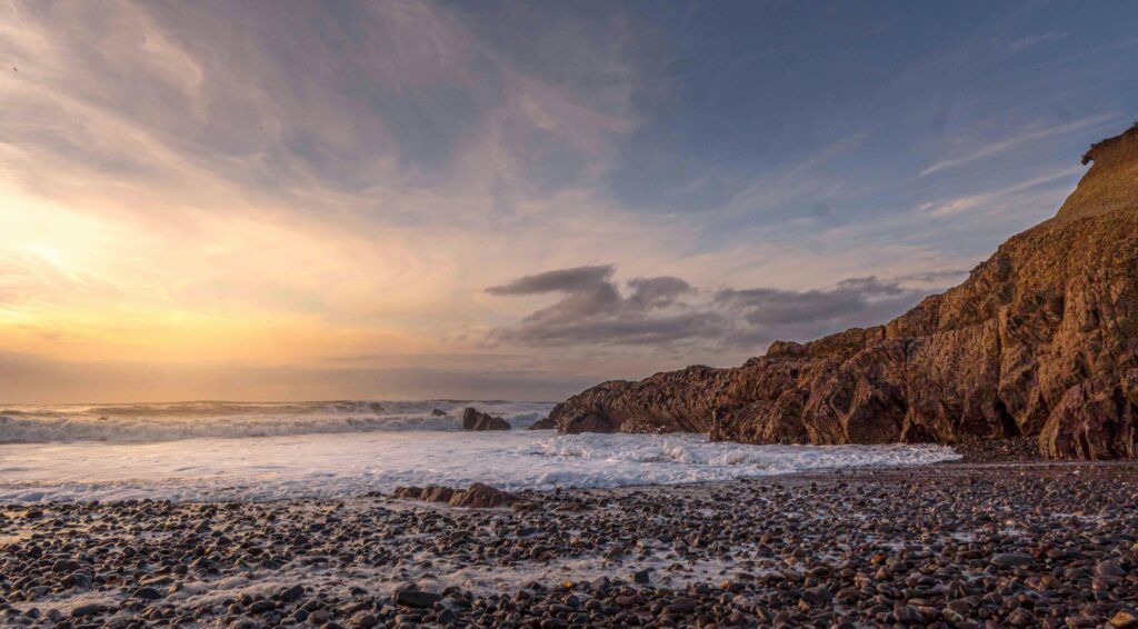 best place to surf in cornwall. sunset of a beach with a rocky outcrop