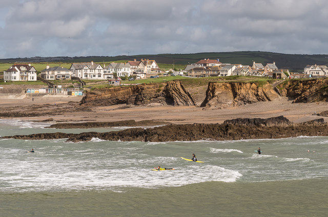 surf lessons uk. surfers paddling out with cross rock and middle beach in the background.