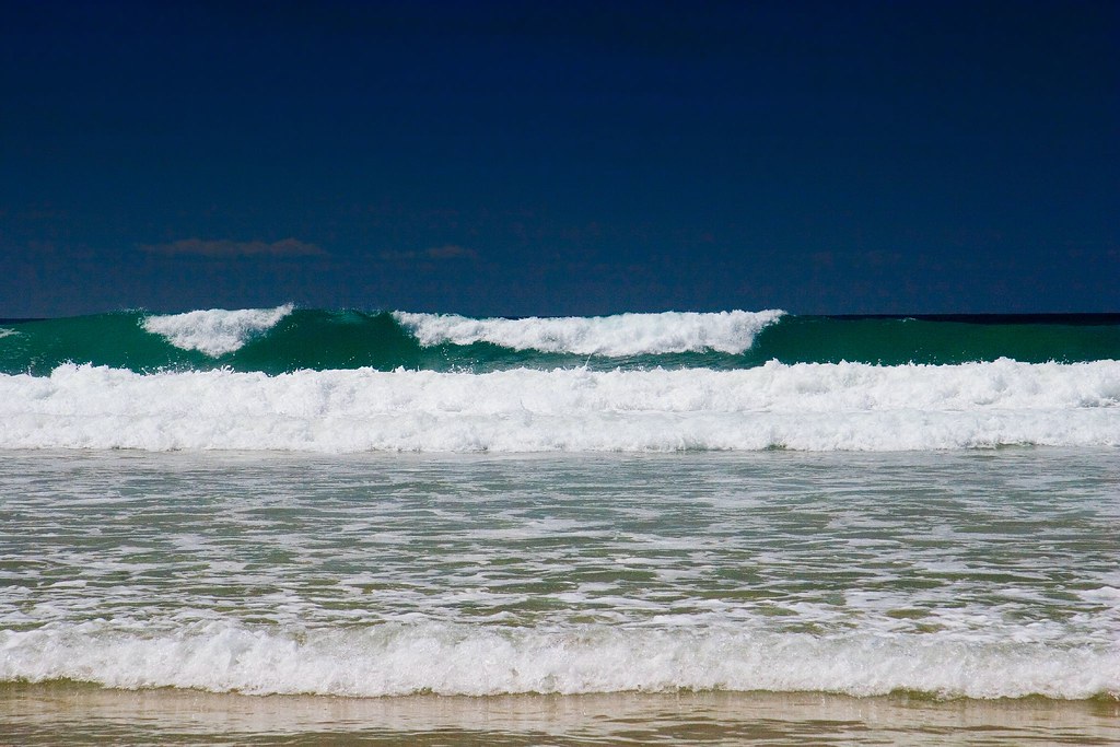 learn to surf england. white water waves roll in on a beach