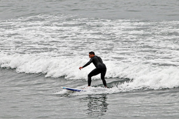 bude surf school. learner surfer riding a small white water wave.