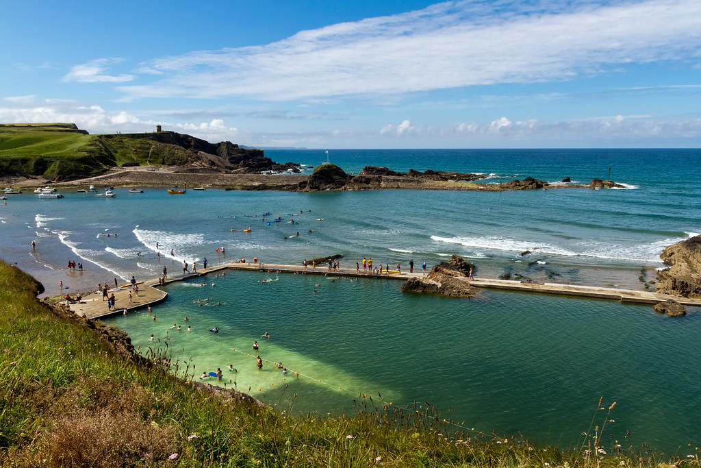 bude surf lessons. cliff top shot of high tide summerleaze looking over the sea pool.