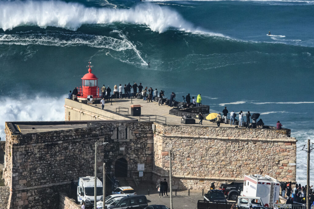 biggest wave to surf. waves breaking at nazare behind the lighthouse.